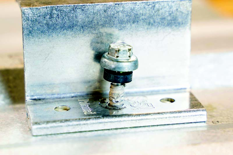 Figure 4: Tacking of butyl tape to a threaded fastener of an S-5!® VersaBracket metal roof attachment.  Photo courtesy of S-5!